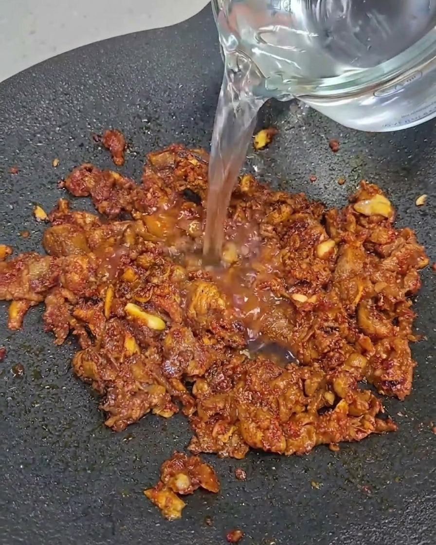 黒いフライパンで牛バラ肉の薄切りを炒めている様子。