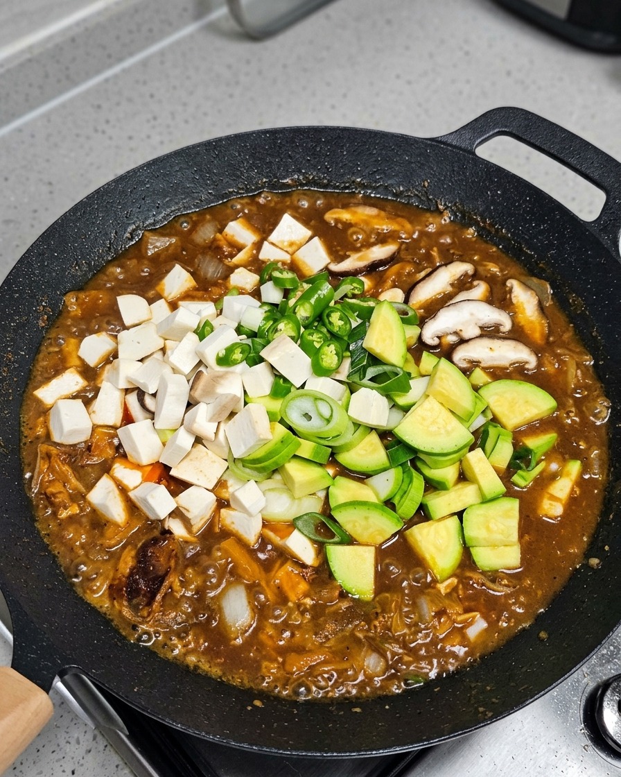 煮立っているスープに野菜と豆腐を加えている様子。