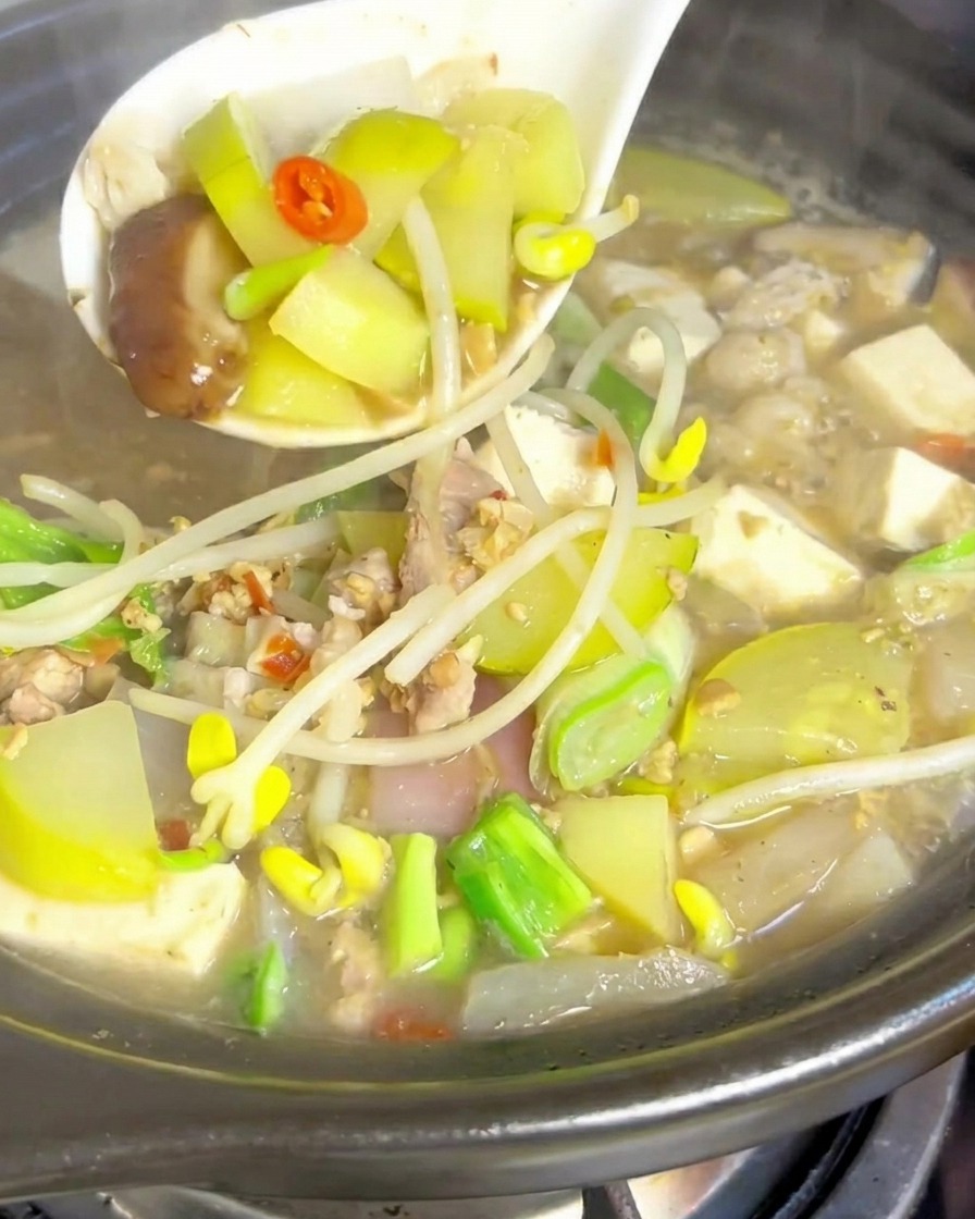 炒めた豚肉が入った土鍋に水を入れている様子。