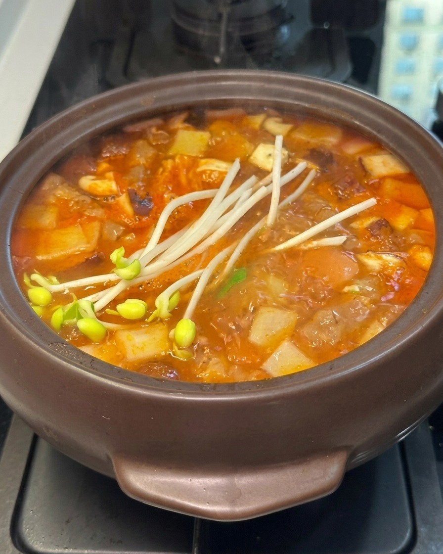 泡立つ鍋の具材の上に、新鮮な豆もやしが加えられている様子。