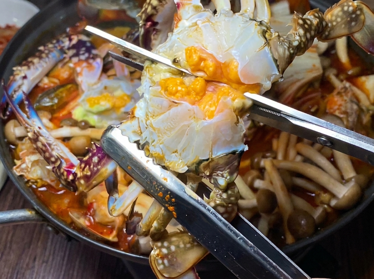 半分に切ったカニを煮込んだ鍋に入れている様子。