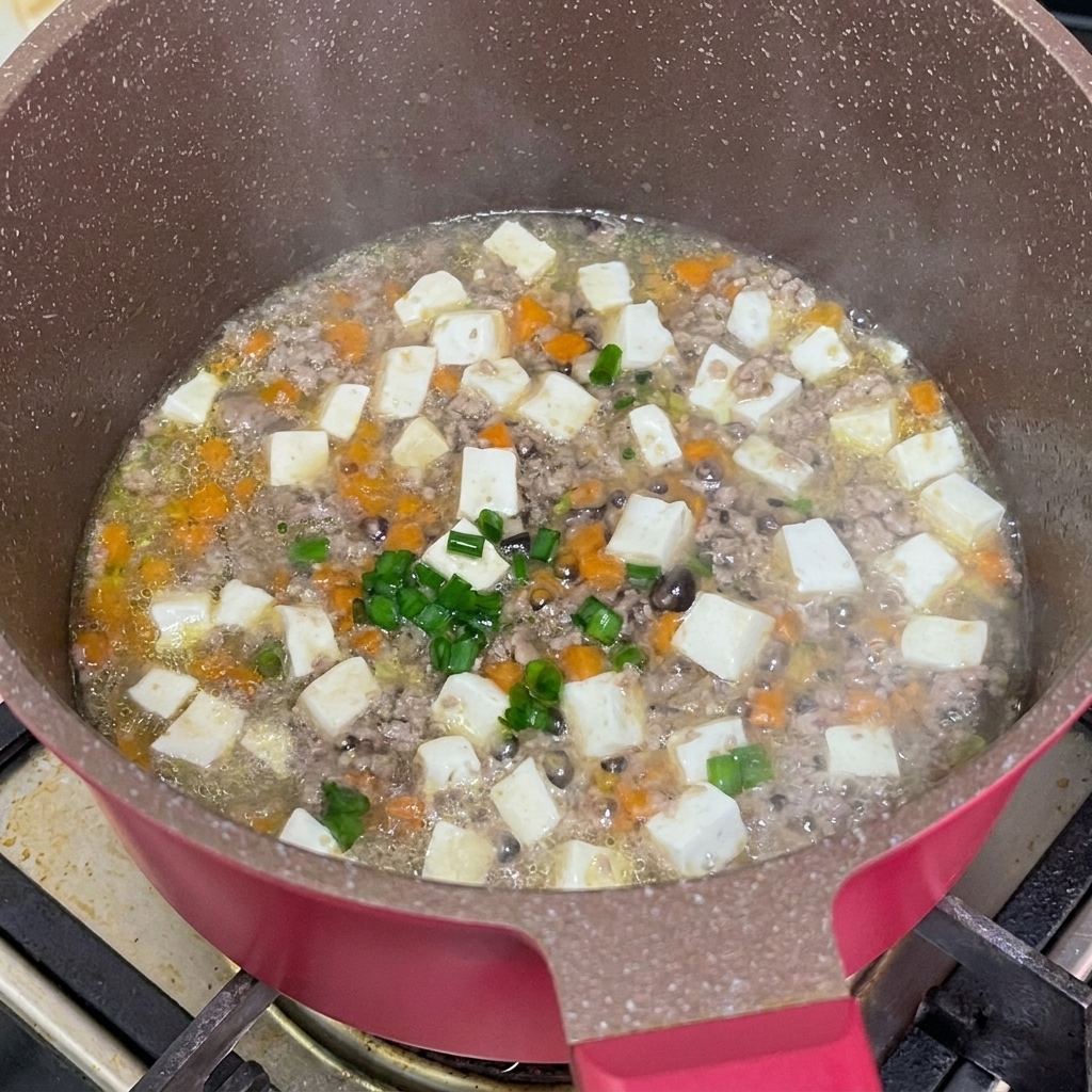 完成した煮込み料理に刻み葱を散らしている様子。