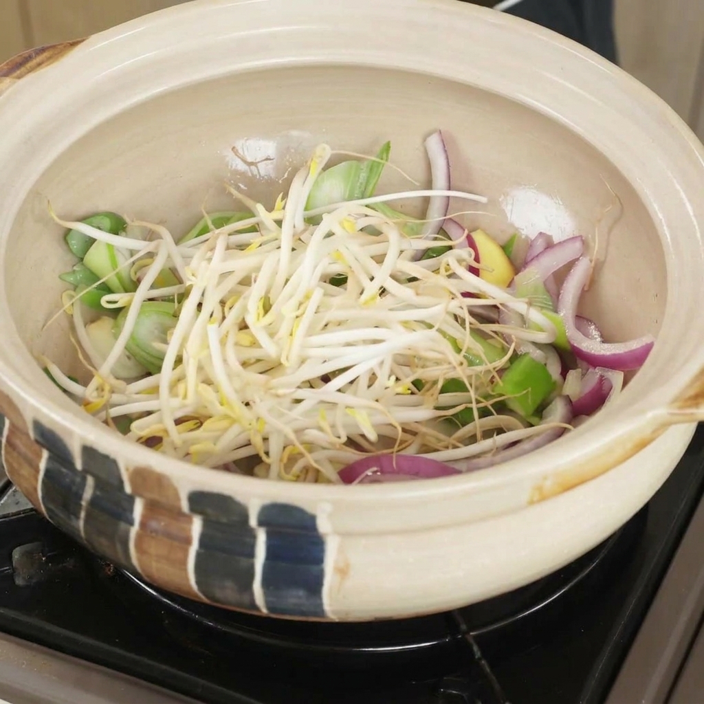 炒めた香味野菜の上にもやしを乗せている様子