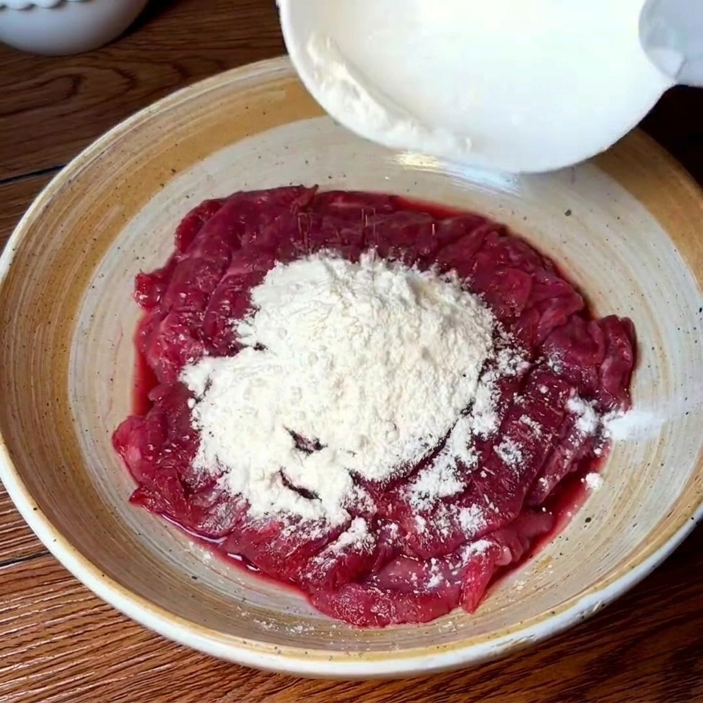 ボウルの中で小麦粉と水を使って牛肉をもみ洗いしている様子。