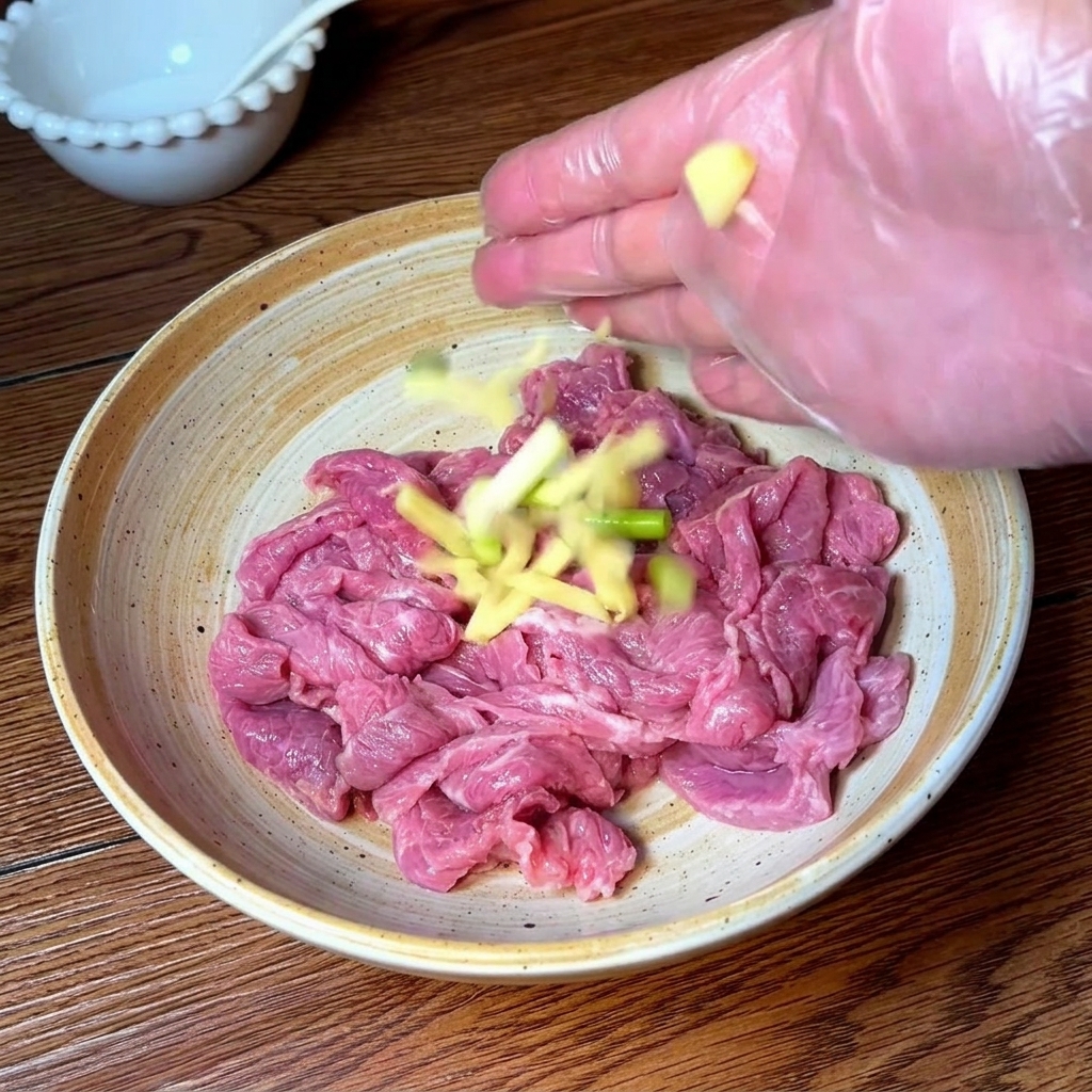 手袋をした手で、牛肉に薬味や調味料を揉み込んでいる様子。