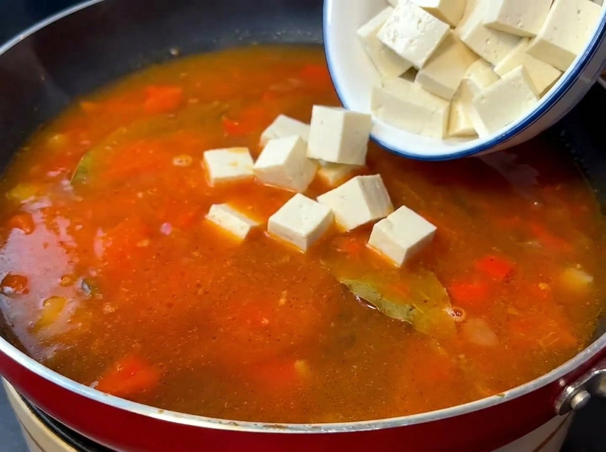 トマトスープのベースに絹ごし豆腐と炒めた牛肉を加えている様子。