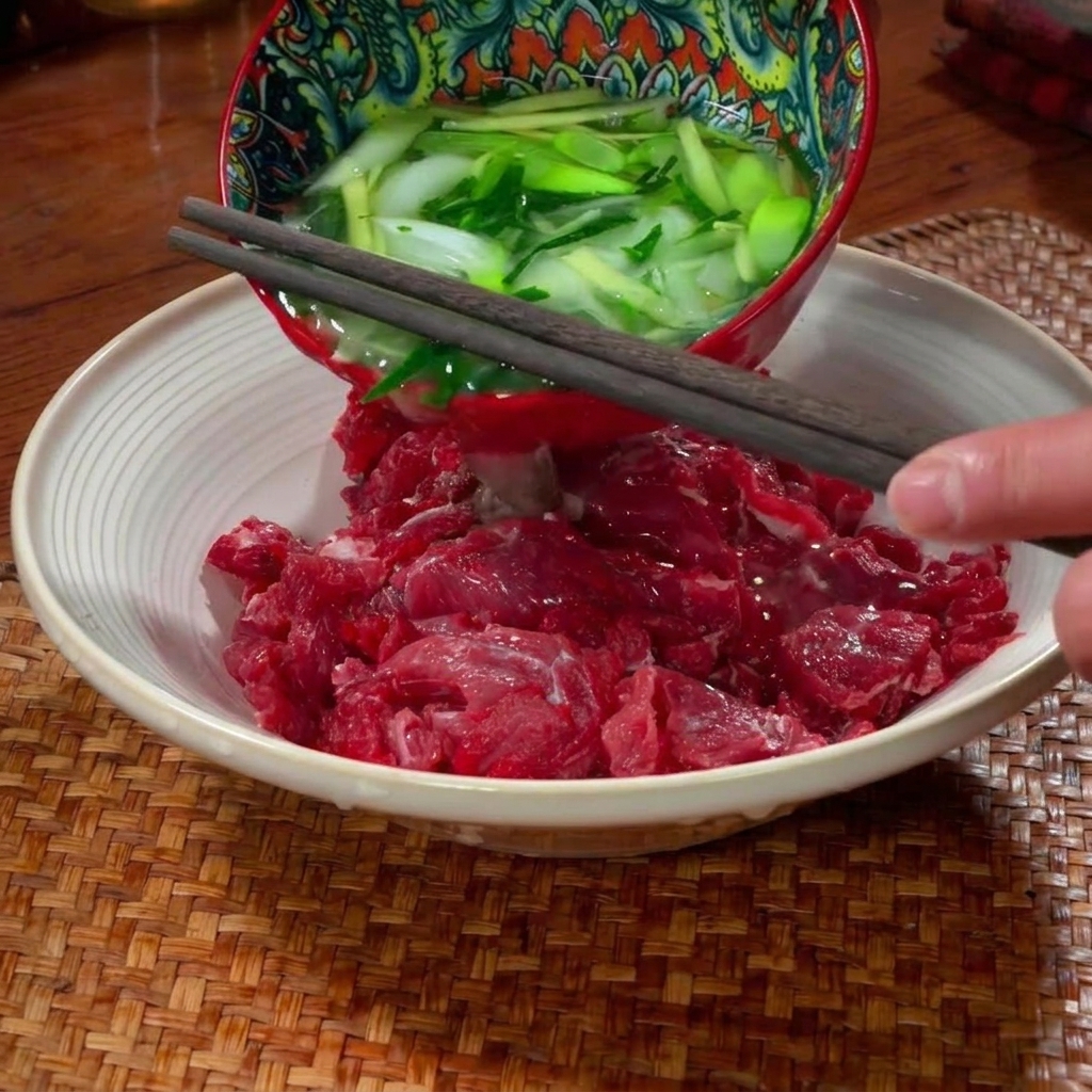 ボウルで牛肉に調味料を揉み込んでいる手元。