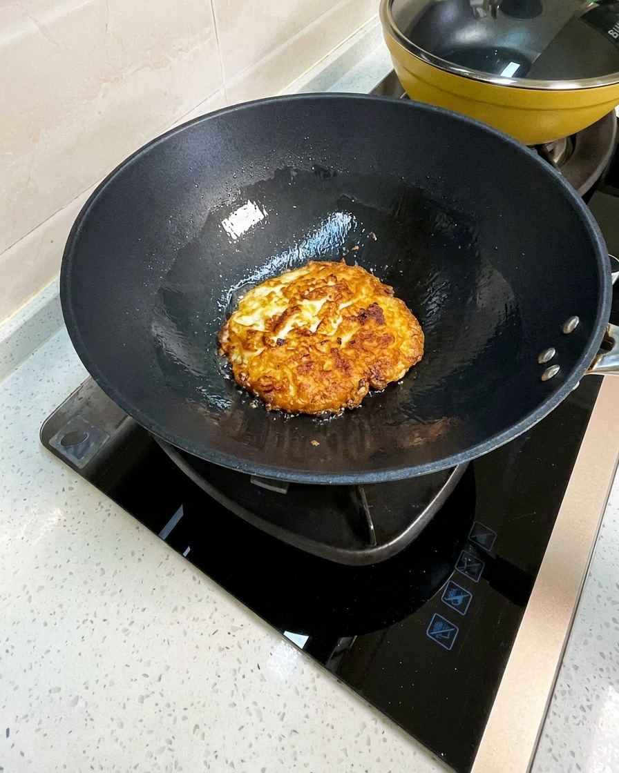 焼いた卵をフライパンの中で大きめに崩している様子。