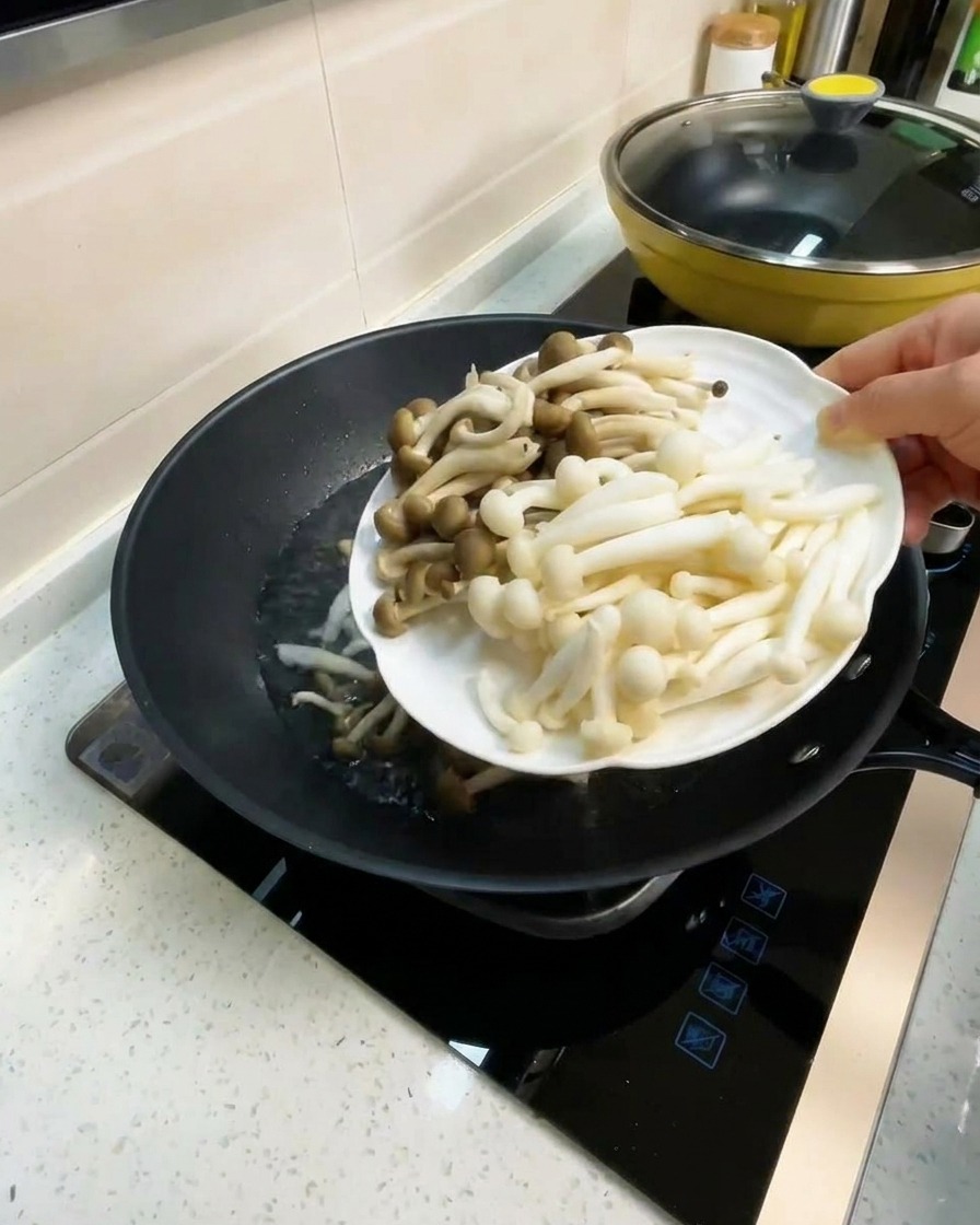 沸騰したスープにキノコと豆腐を加えている様子。