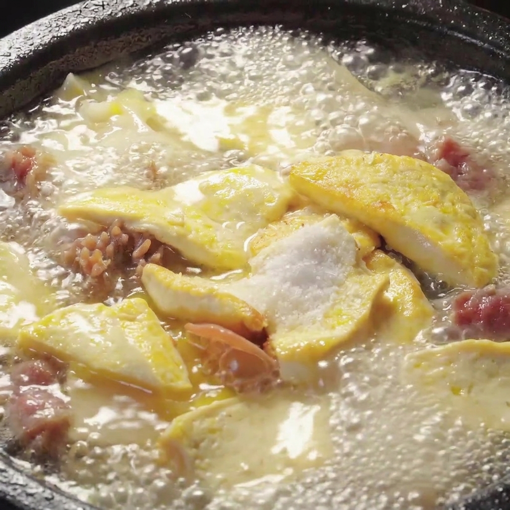 煮立っているきのこ豆腐スープに調味料を加えてかき混ぜている様子。