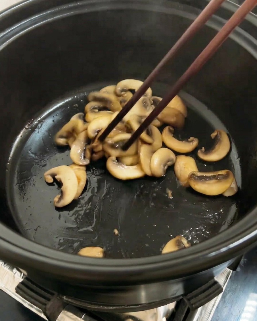 炒めたキノコと一緒に、ざく切りトマトを鍋に加えている様子。