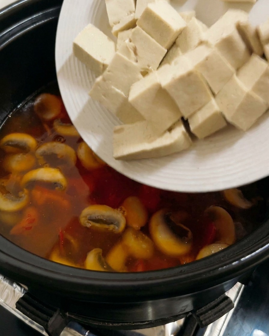 トマトベースのスープに、豆腐を加えている様子。