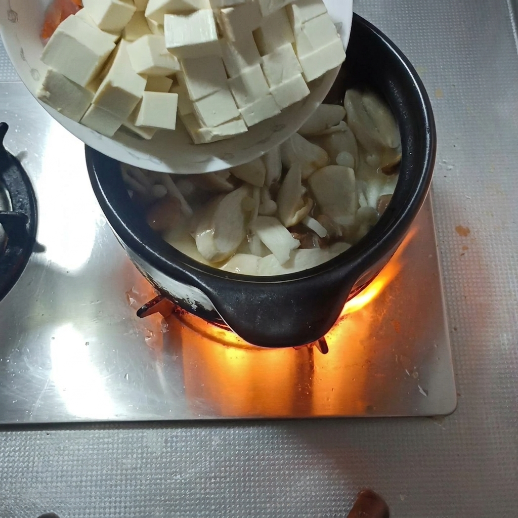 角切りにした絹ごし豆腐と人参をスープに加える様子。