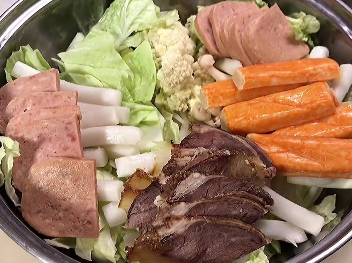 他の食材の上にさつま揚げとエビを置いている様子