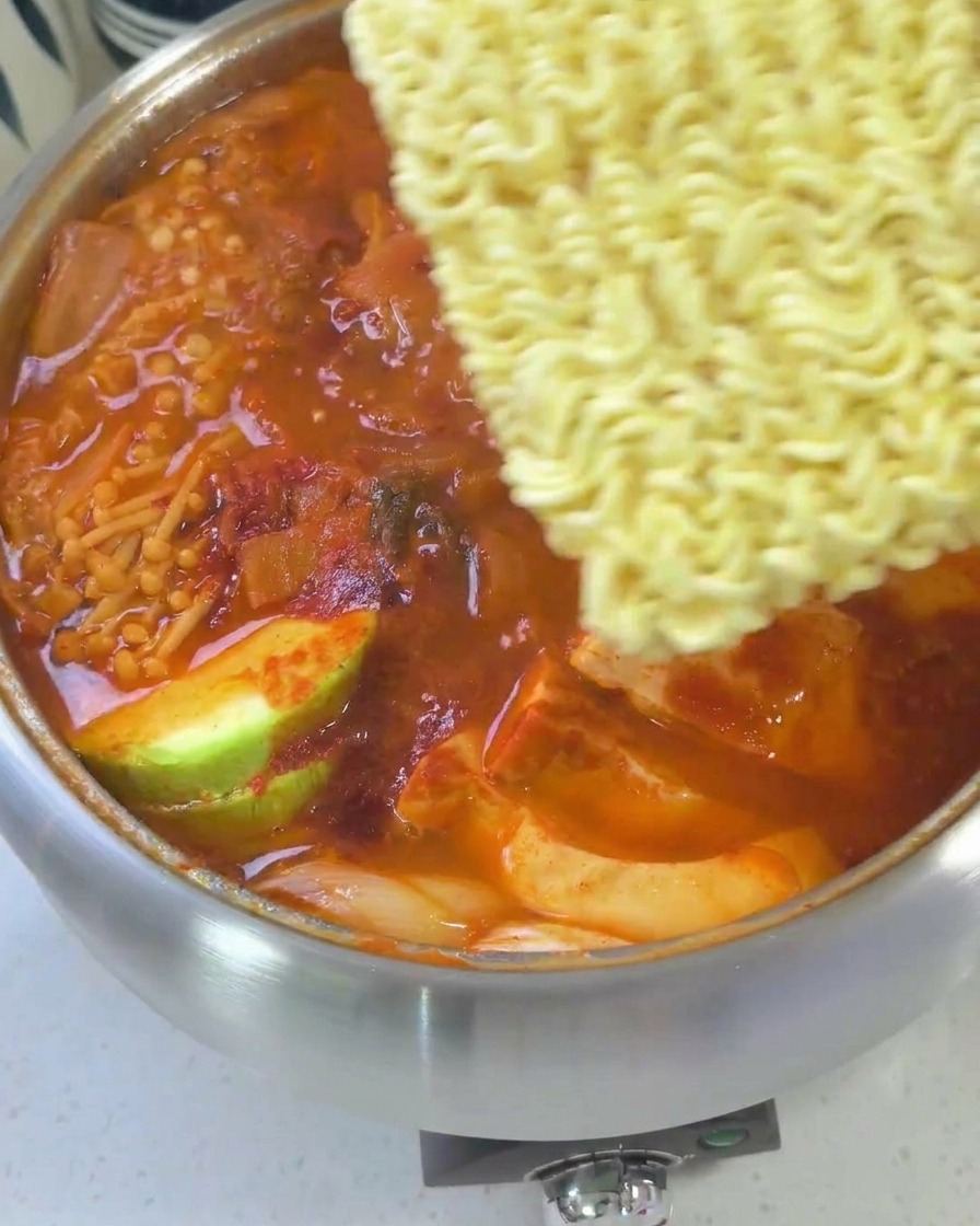 煮上がった鍋に、ラーメン、チーズ、卵がのせられた完成直前の様子。