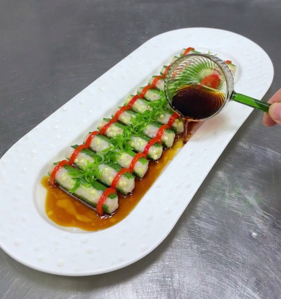 蒸し上がった料理の上に、お玉で醤油を回しかけている様子。