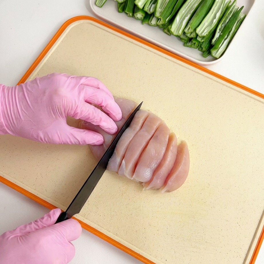まな板の上で、鶏むね肉を細かく切り分けている様子。