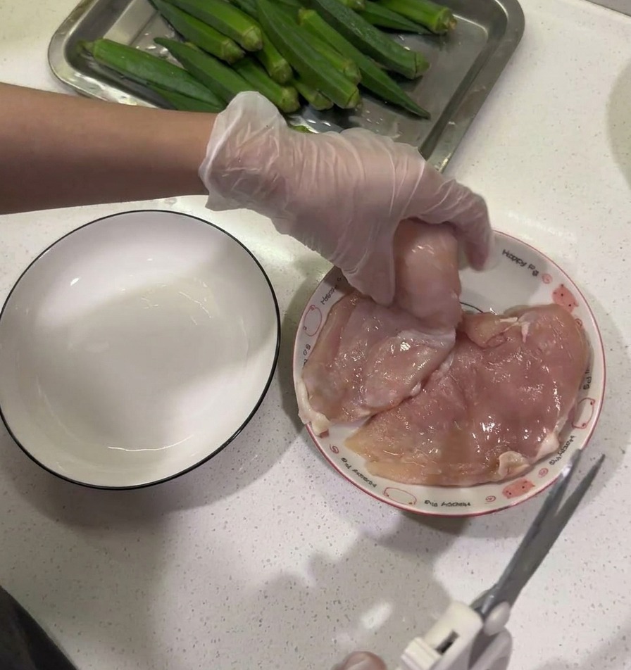 キッチンバサミを使って鶏むね肉から脂肪を取り除いている様子。