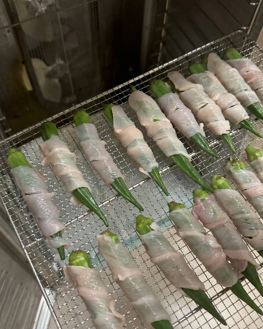 乾燥機のステンレス製トレイに整列した鶏肉巻きオクラ。