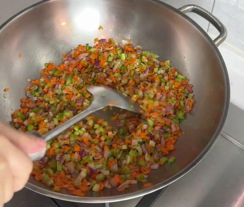 にんにく、にんじん、セロリ、玉ねぎをフライパンで炒めている色鮮やかな様子。