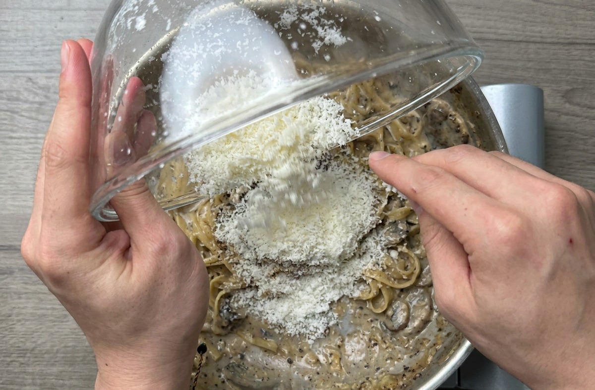 フライパンを煽り、パスタを激しく混ぜることでソースに艶が出ているクローズアップ写真。
