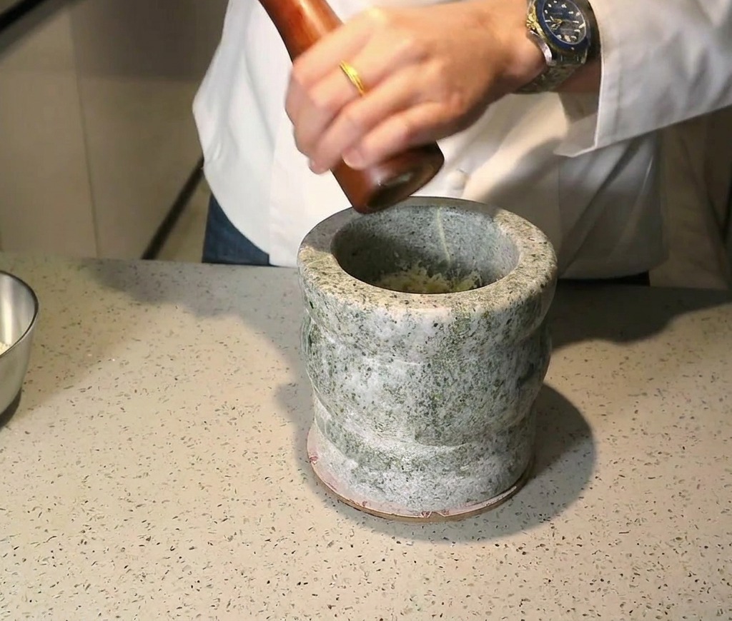 すり鉢の中の材料に黒胡椒を挽いている様子。