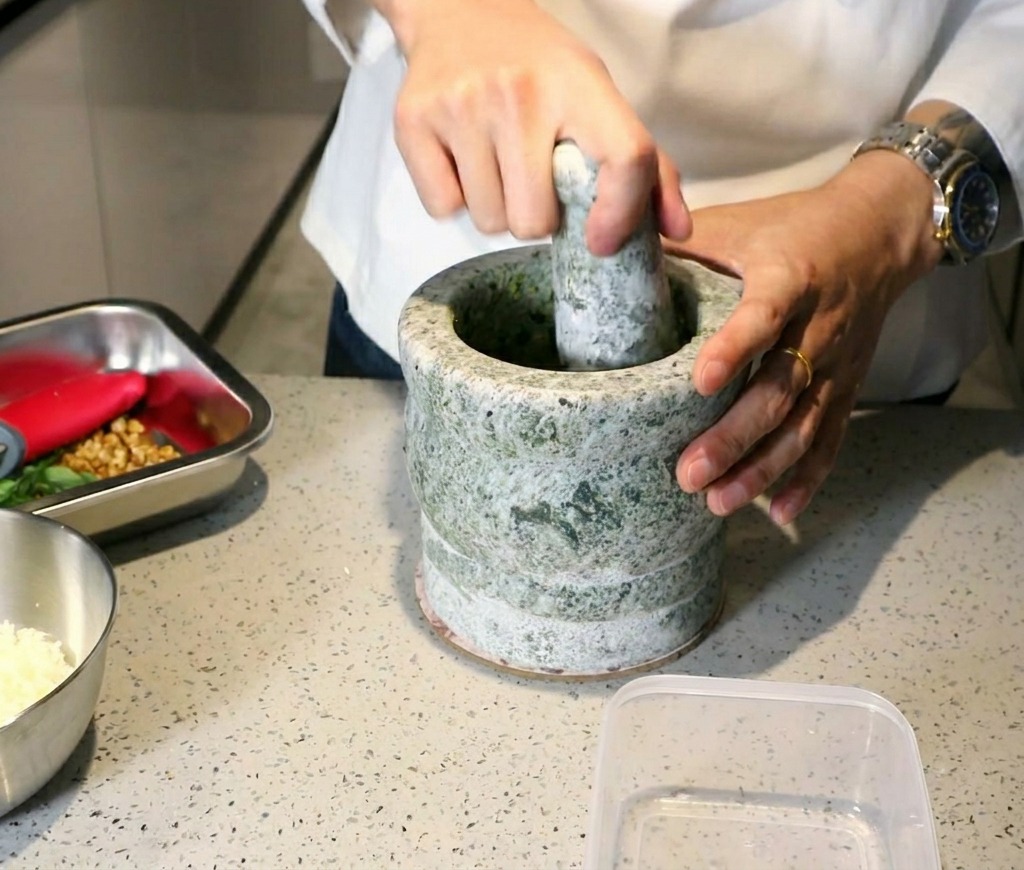 すり鉢とすりこぎを使い、滑らかなバジルペーストを作っている様子。