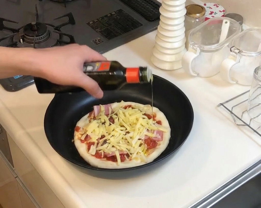 チーズの上に仕上げのオイルを垂らし、フライパンでピザを焼いているクローズアップ。