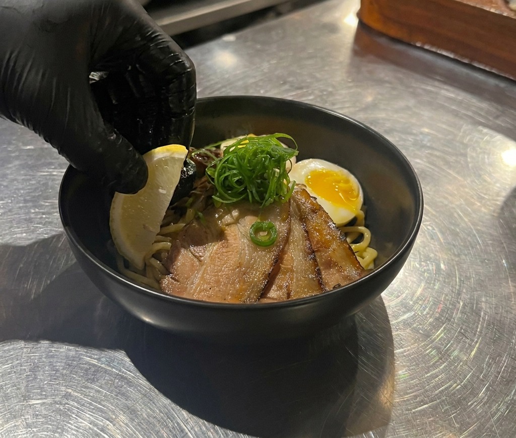 具材が美しく盛り付けられた器の端に、鮮やかな黄色のレモンを添える様子。