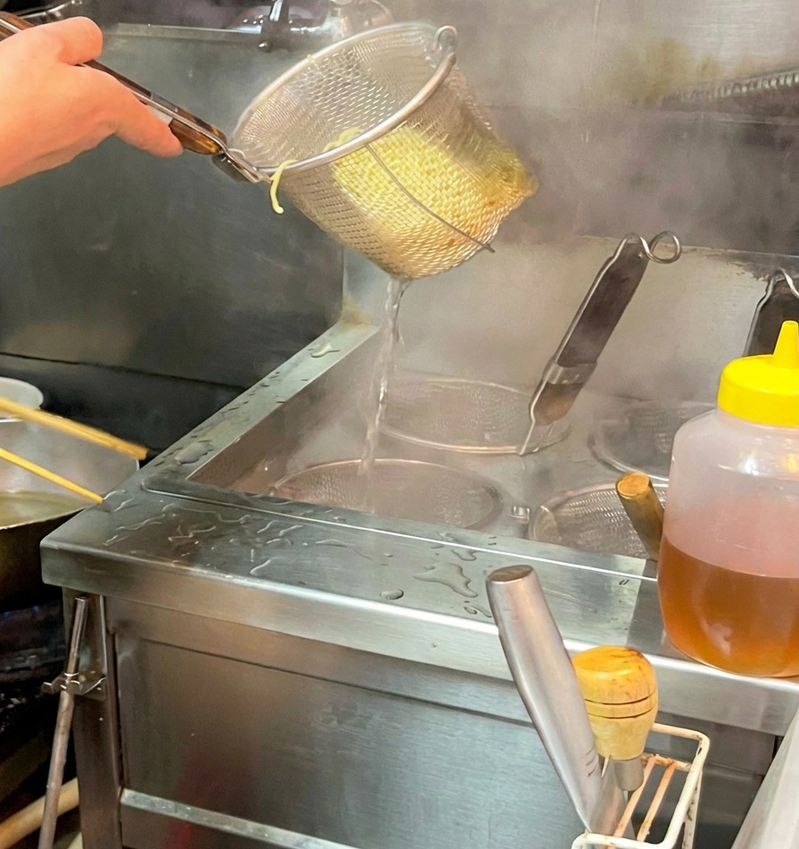 湯切りした麺を、スープが入った丼に静かに移している様子。