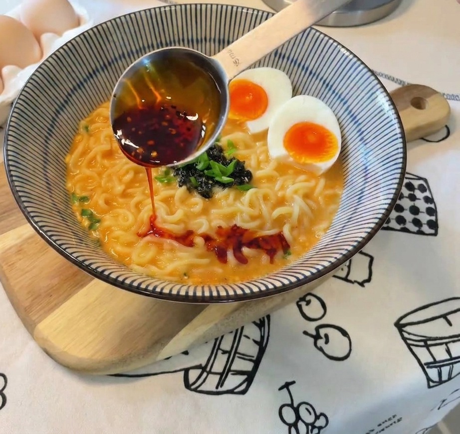 赤いラー油をラーメン全体に回しかけている仕上げの様子。