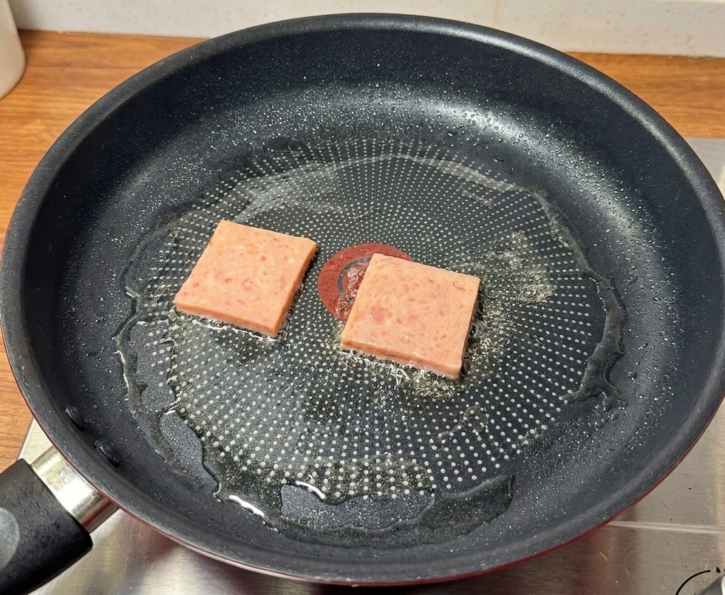 フライパンの中で、ランチョンミートに美味しそうな焼き色がつくまで焼いている様子。