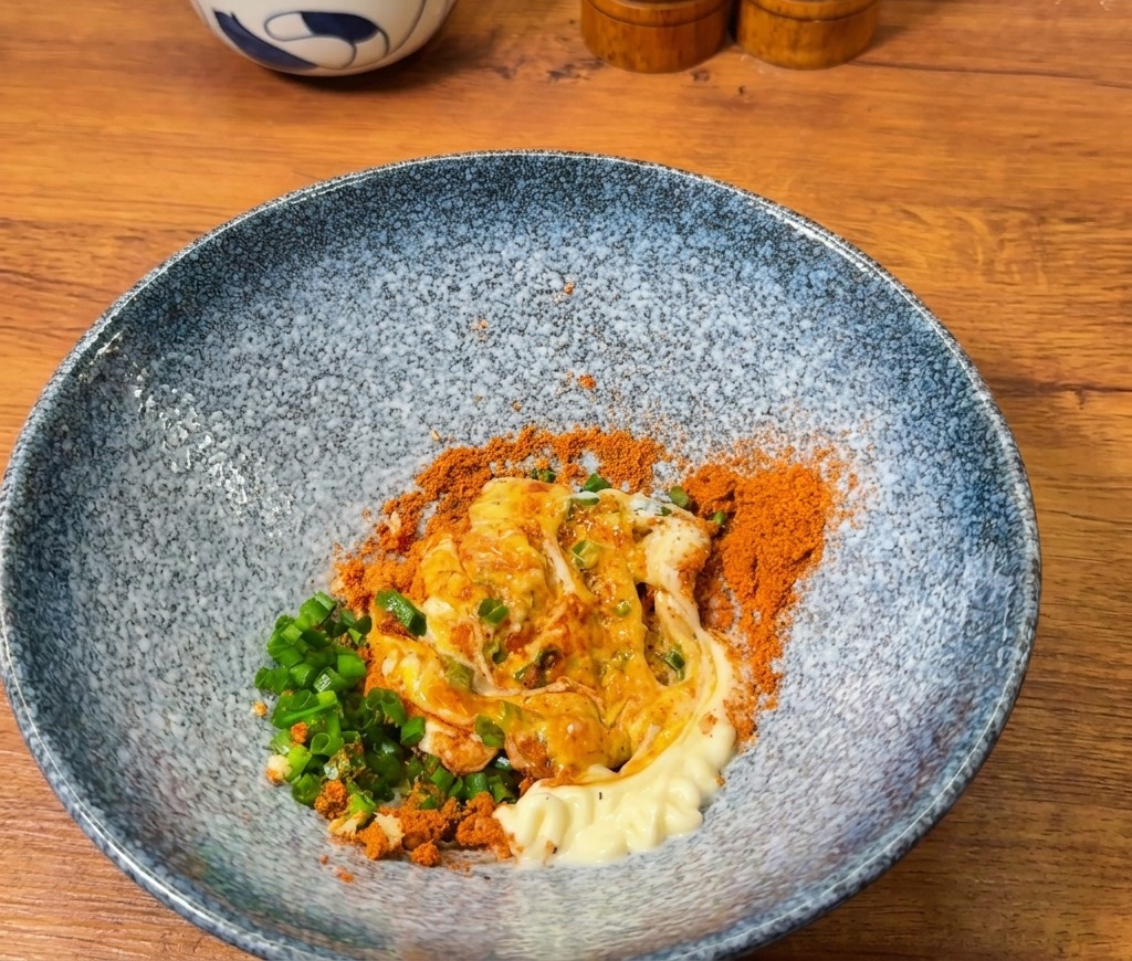 オレンジ色の調味料に、真っ白なマヨネーズを加えて混ぜ合わせている様子。