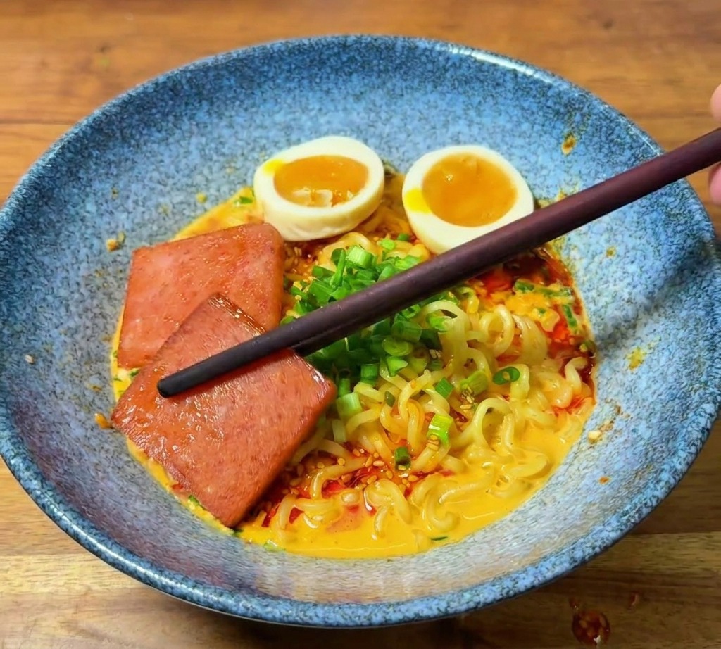 焼いたランチョンミートを、箸で器の縁に盛り付けている様子。