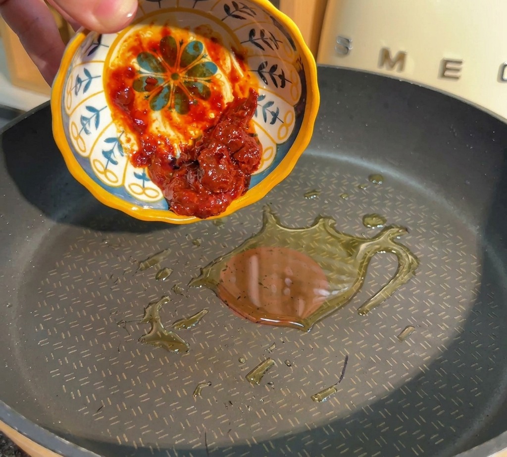 熱したフライパンに豆板醤を入れ、木べらで炒めている様子。