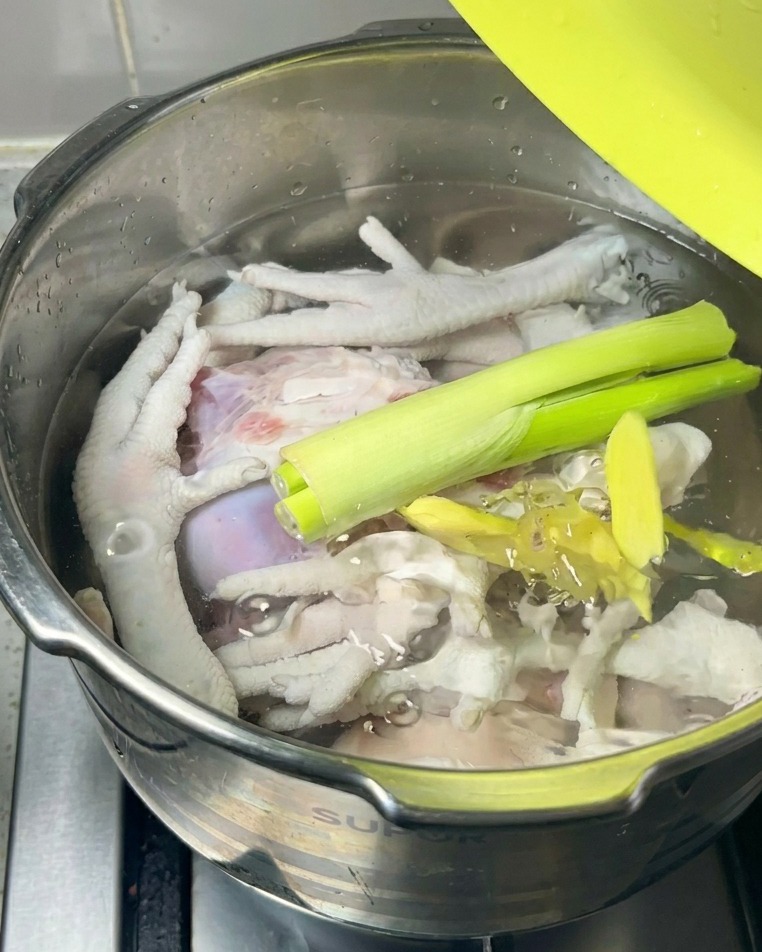 生の肉と水の上に、長ねぎと生姜のスライスがのっている様子。