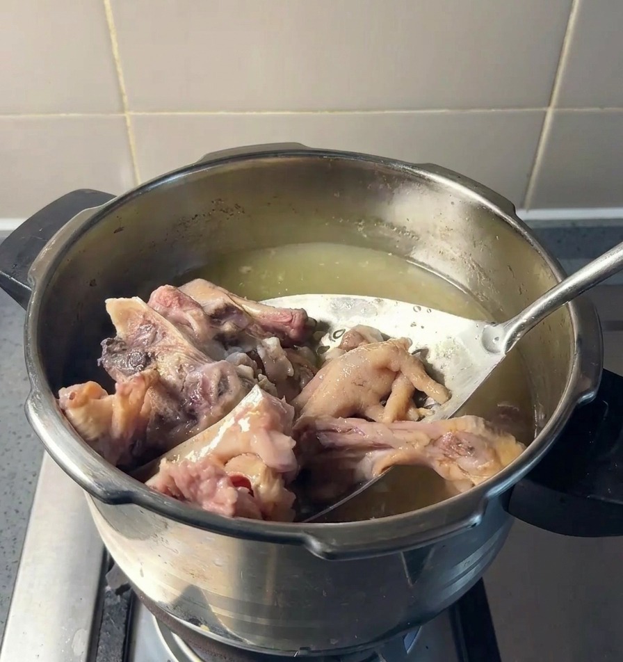 穴あきお玉で、煮上がった豚骨や鶏足を鍋から取り出している様子。