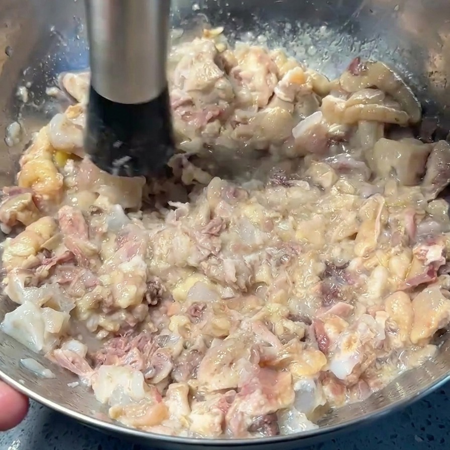 マッシャーを使い、ボウルの底で肉と皮を細かく潰している様子。