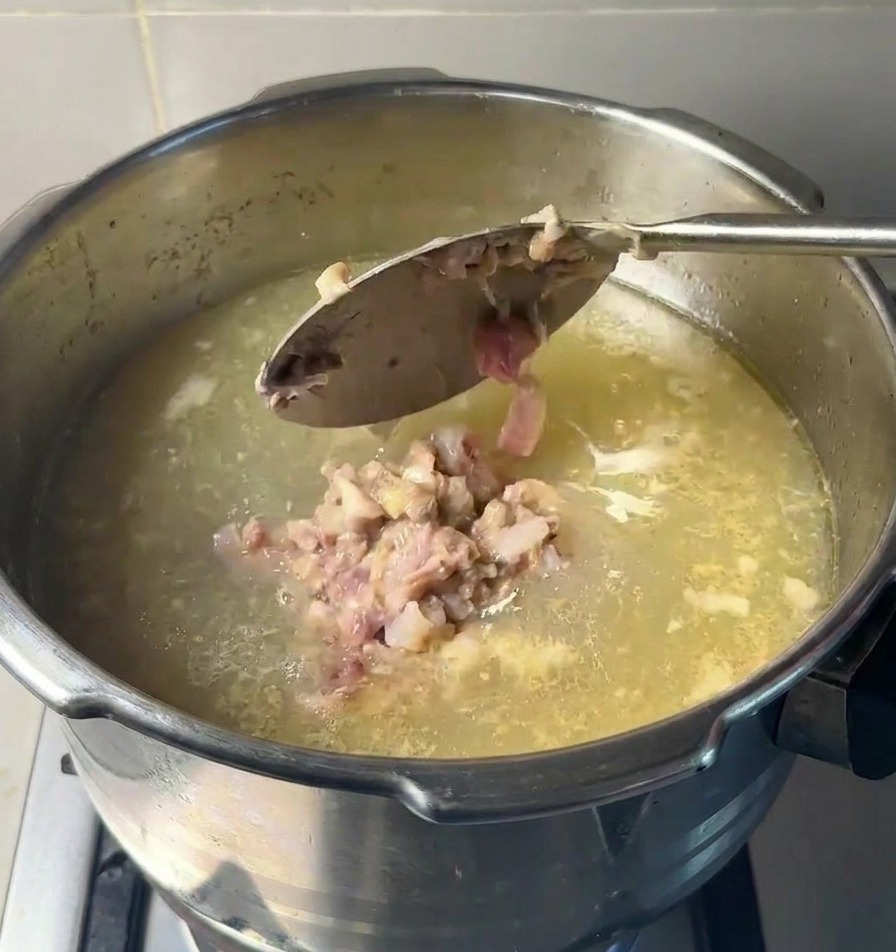 お玉で、潰した肉と骨髄をスープの入った鍋に戻し入れている様子。