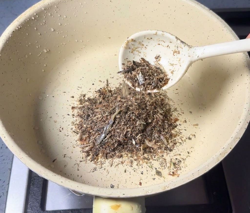 小さな鍋に挽きたての魚粉をスプーンで入れている様子