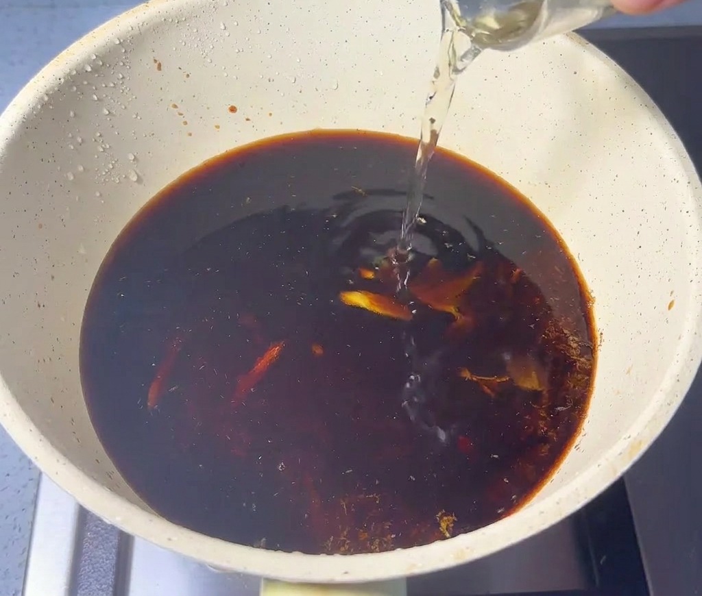醤油と魚粉の入った鍋にみりんと酒を注ぐ様子