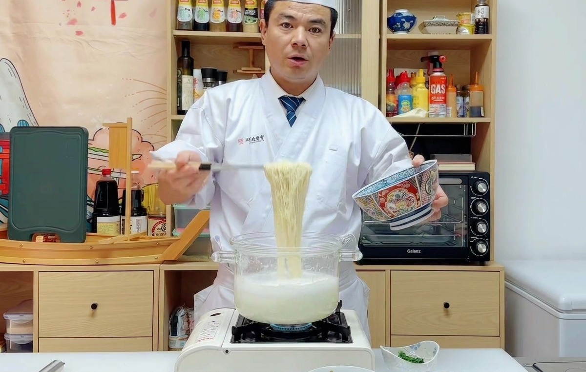 茹で上がった麺を湯切りし、青い模様のどんぶりに移している様子。