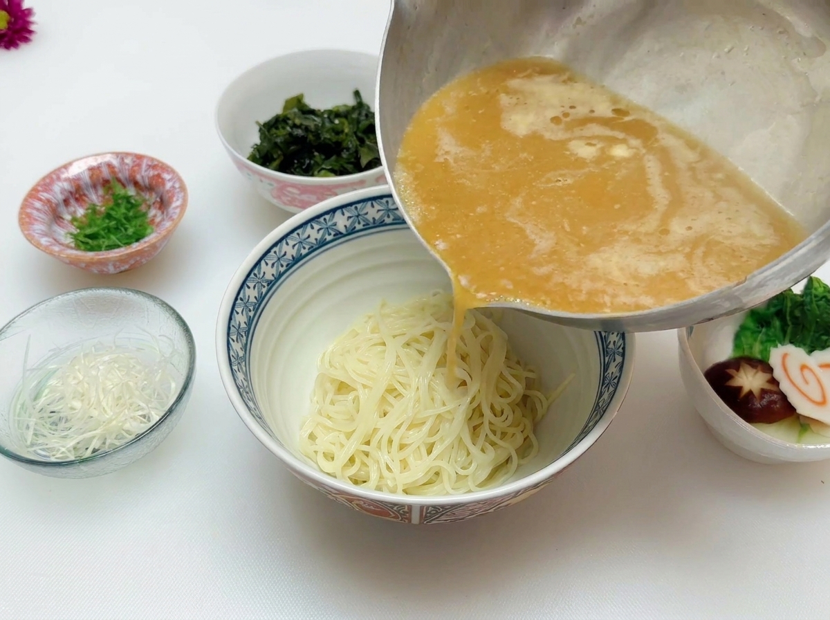 どんぶりに入った麺の上から、熱々の味噌スープを注いでいる様子。
