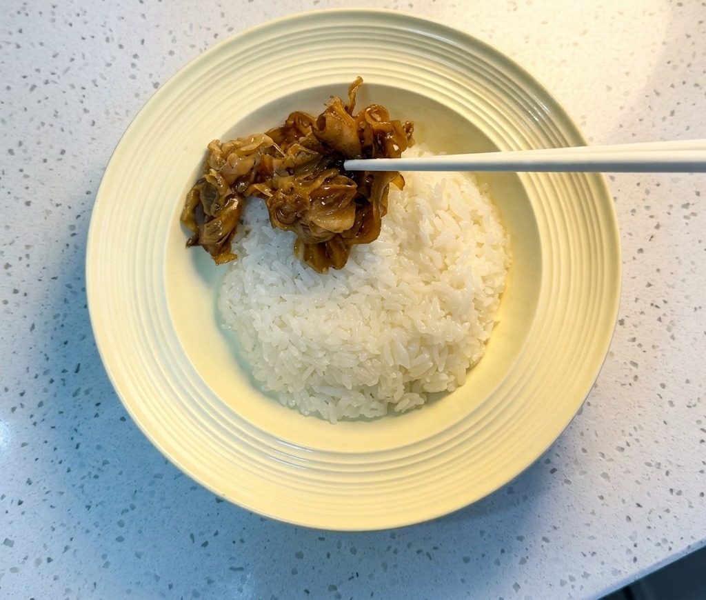 ご飯の上に、箸で具材をバランスよく盛り付けている様子。