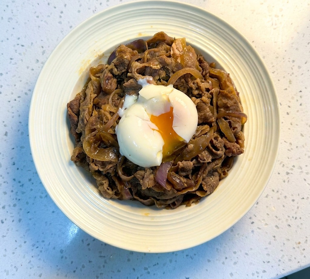 中央に温泉卵をのせ、黒ごまを散らした完成した牛丼。