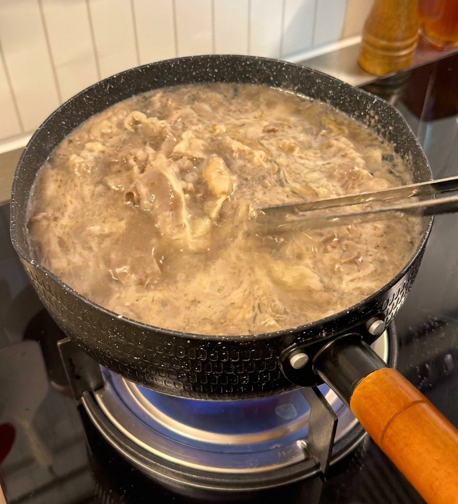 茹でた牛肉をトングで取り出している様子。