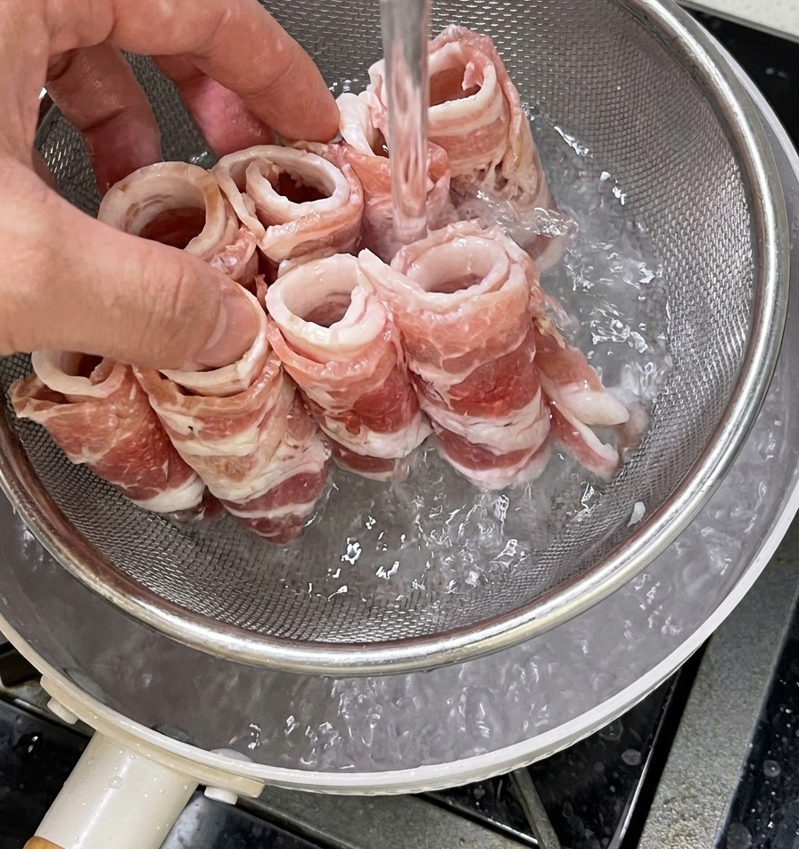 網じゃくしに乗せた牛肉を沸騰したお湯に入れ、色が変わり始める様子。