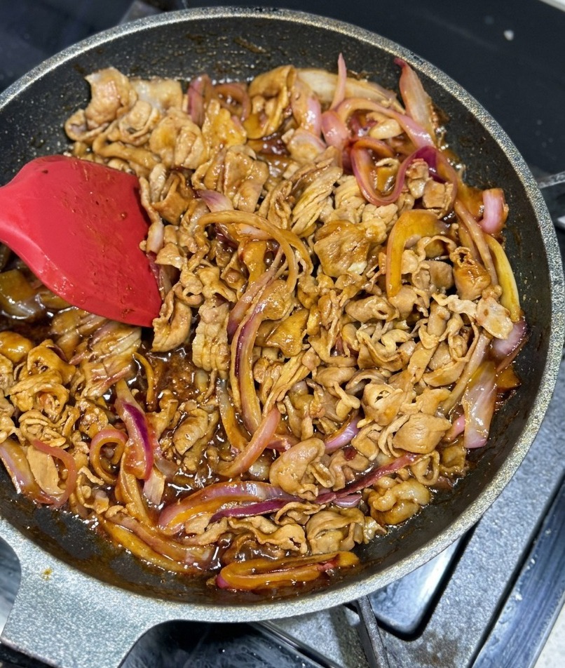 肉と玉ねぎが濃い茶色のつやつやしたタレにしっかりとコーティングされている様子。
