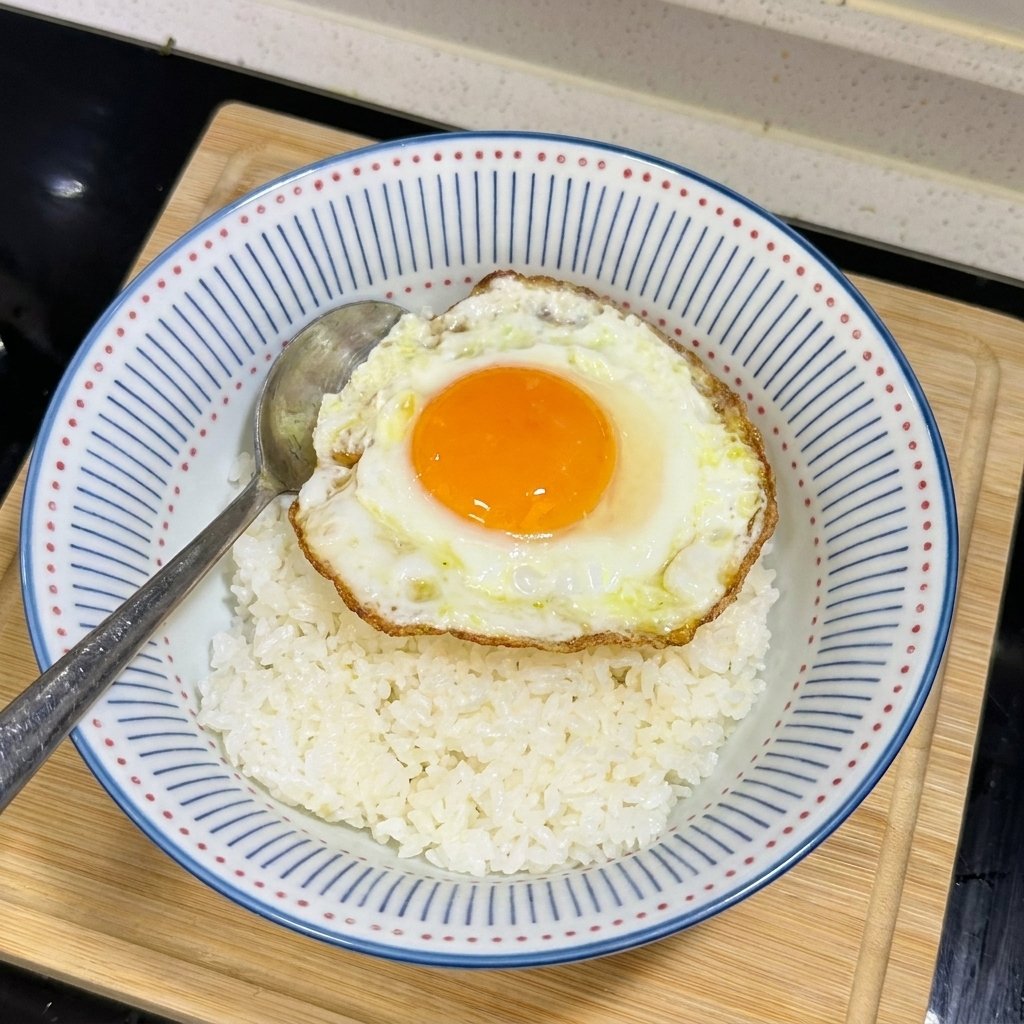 白いご飯の上に、黄身が半熟で縁がカリッとした目玉焼きが乗っている様子。