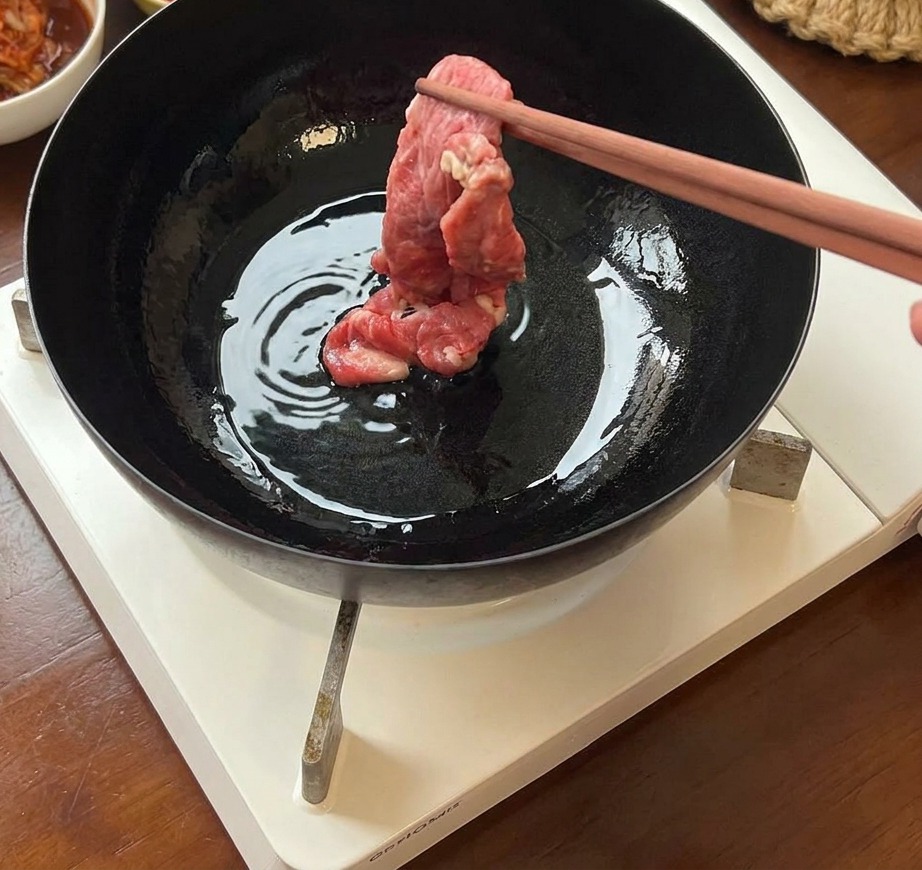 熱したフライパンに牛肉の薄切りを入れて焼く様子。